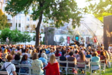 Koncert muzyki filmowej. Ludzie siedzą na krzesłach przed sceną.